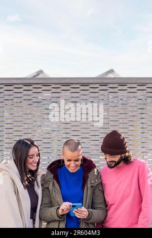 three young friends smiling happy using a phone Stock Photo