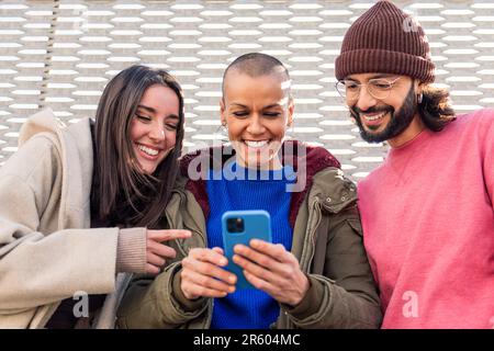 three young friends smiling happy using a phone Stock Photo