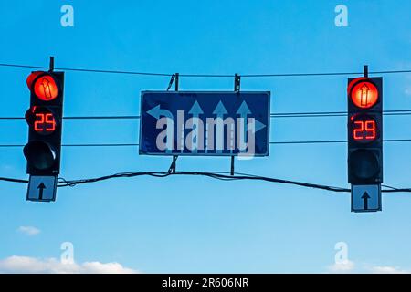 two lights a back-up red light with road signs against a blue evening sky Stock Photo