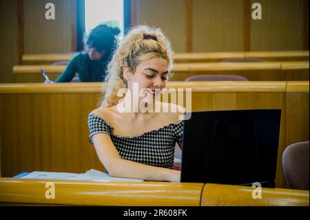 Smiling young woman using laptop in classroom Stock Photo