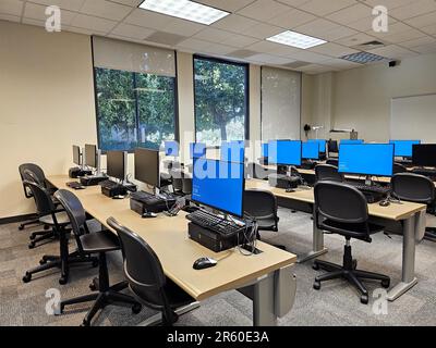 A modern classroom with computer monitors situated on desks. Stock Photo