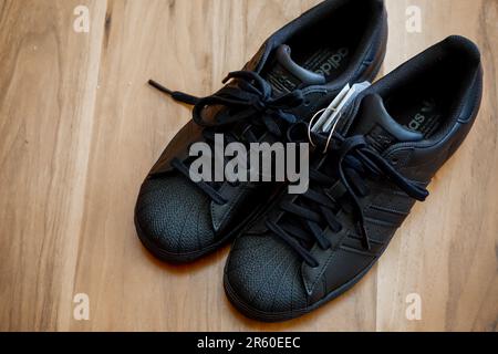 10 July 2022 Eskisehir Turkey.Brand new black adidas superstar shoes on wooden background Stock Photo