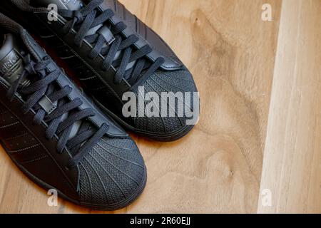 10 July 2022 Eskisehir Turkey.Brand new black adidas superstar shoes on wooden background Stock Photo