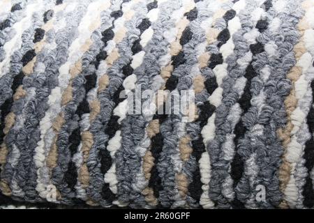 Close-up of a multi-colored striped carpet with thick woven loops. Features a vibrant mix  blue, grey, brown, and white tones. Stock Photo