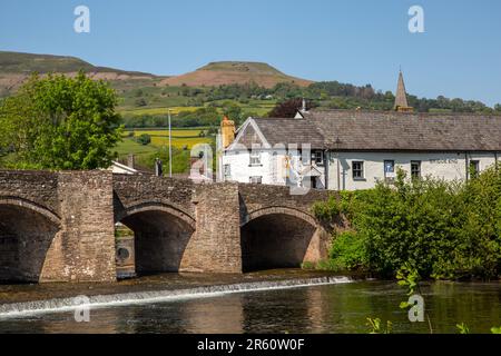 The river Usk flowing under the ancient Crickhowell Bridge in the South Wales town of Crickhowell Powys, with Table mountain rising above the town Stock Photo