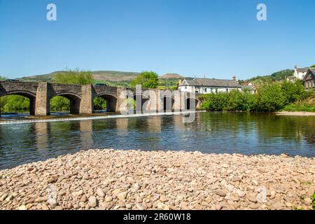 The river Usk flowing under the ancient Crickhowell Bridge in the South Wales town of Crickhowell Powys, with Table mountain rising above the town Stock Photo