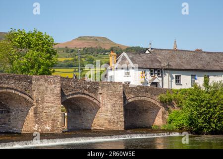 The river Usk flowing under the ancient Crickhowell Bridge in the South Wales town of Crickhowell Powys, with Table mountain rising above the town Stock Photo