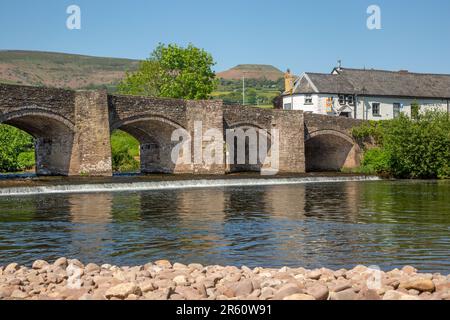 The river Usk flowing under the ancient Crickhowell Bridge in the South Wales town of Crickhowell Powys, with Table mountain rising above the town Stock Photo