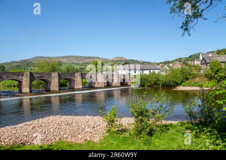 The river Usk flowing under the ancient Crickhowell Bridge in the South Wales town of Crickhowell Powys, with Table mountain rising above the town Stock Photo