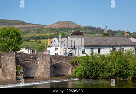 The river Usk flowing under the ancient Crickhowell Bridge in the South Wales town of Crickhowell Powys, with Table mountain rising above the town Stock Photo