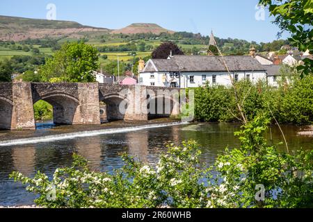 The river Usk flowing under the ancient Crickhowell Bridge in the South Wales town of Crickhowell Powys, with Table mountain rising above the town Stock Photo