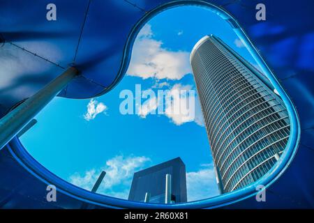 A circular mirror reflects the exterior of a cityscape, with tall buildings in the background Stock Photo