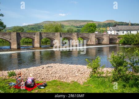 The river Usk flowing under the ancient Crickhowell Bridge in the South Wales town of Crickhowell Powys, with Table mountain rising above the town Stock Photo