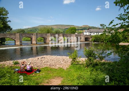 The river Usk flowing under the ancient Crickhowell Bridge in the South Wales town of Crickhowell Powys, with Table mountain rising above the town Stock Photo