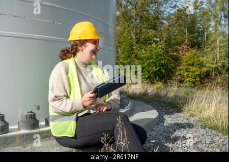 A female construction worker with protective equipment taking a break in the shade Stock Photo