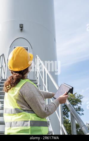 A female engineer using a tablet while wearing protective gear and a hard hat. Stock Photo