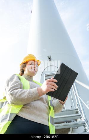 A construction worker wearing a hard hat and in front of a tall tower Stock Photo