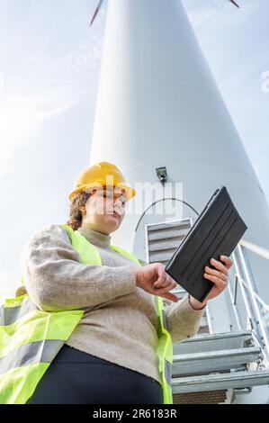 A female professional wearing a yellow safety helmet is using a tablet Stock Photo