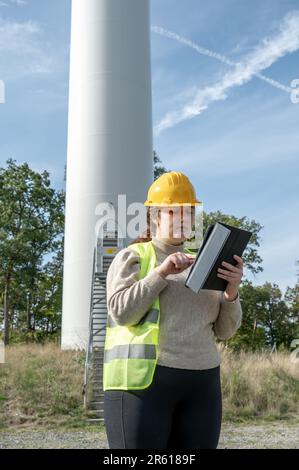 A female engineer in a safety hat is intently focused on her tablet Stock Photo