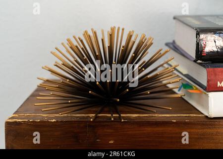 A traditional wooden desk with a stack of books neatly arranged on top of it, situated next to a bookshelf filled with various educational texts Stock Photo