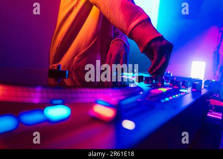 Hands of a DJ creating and regulating music on dj console mixer at club concert Stock Photo