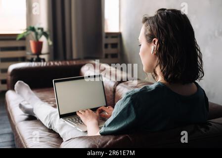 Home Office Productivity: Young Woman Engaged in Laptop Work, Studying, and Freelancing from the Comfort of Her Room, Embracing the Lifestyle of Remot Stock Photo