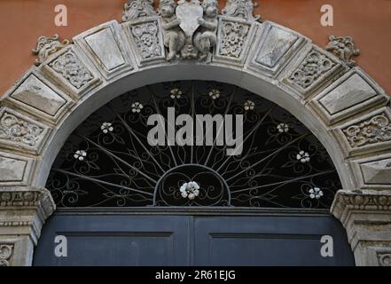 Arched molded entrance gate with wrought iron grilles on a venetian stucco wall.