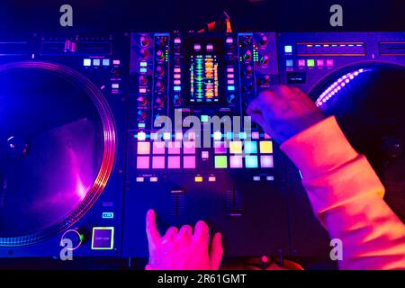 Hands of a DJ creating and regulating music on dj console mixer at club concert Stock Photo