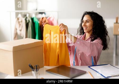 Successful Designer Lady Holding Trendy Garment Packing Order Sitting Indoor Stock Photo