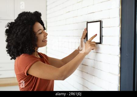 Innovative Technology. Black Woman Using Blank Digital Tablet For Smart Home Settigns Stock Photo
