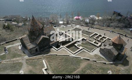 Sevanank Monastery Complex in Armenia. Monastery buildings with crosses, view from above, against the background of Lake Sevan, houses, people, high s Stock Photo