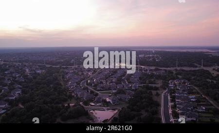 An aerial view of houses and roads on green hills at purple sunset Stock Photo