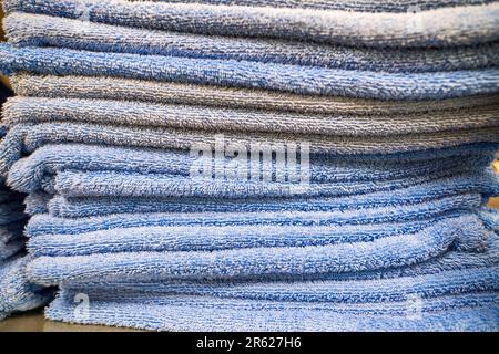 Clean terry soft towels in light blue colors folded, stacked in a pile. Stacks of towels stacked on shelves in the laundry room. Stock Photo