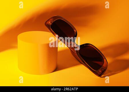 Podium with stylish sunglasses on orange background Stock Photo