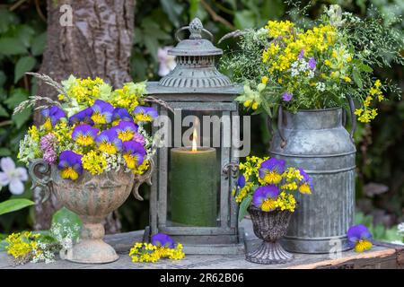 floral arrangement with bouquets of blue viola flowers, yellow bedstraw and meadow flowers in vintage vases Stock Photo