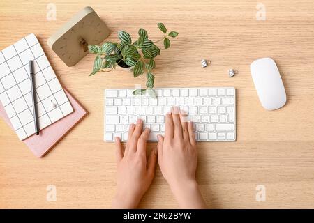 Female programmer using computer keyboard with clock and mouse on wooden background Stock Photo