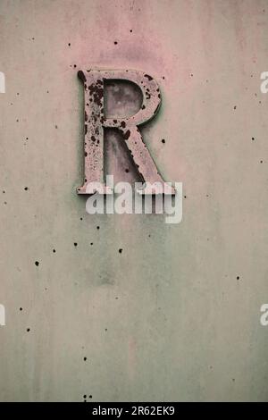 The capital letter R carved into a copper metal wall in a black and ...