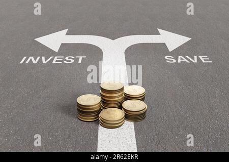 Stacks of gold coins on a traffic lane with split arrows pointing to left with the word INVEST and to the right with the word SAVE. Financial decision Stock Photo