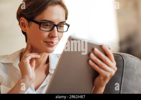 Close-up of a businesswoman in eyeglasses using a digital tablet. Portrait of a female with a digital tablet. Stock Photo