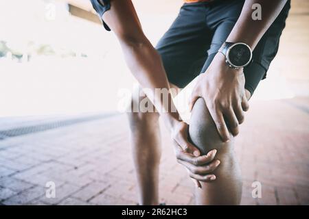Leg day really let me down. a man experiencing joint pain while working out against an urban background. Stock Photo