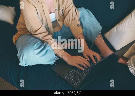 Logout of the old, login to the new. an unrecognisable woman using a laptop on the sofa at home. Stock Photo
