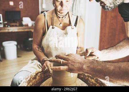 Make more art, have more fun. a young man and woman working with clay in a pottery studio. Stock Photo