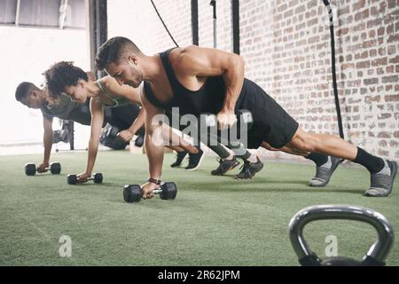 Strengthen your grip. a fitness group using dumbbells while doing push-ups at the gym. Stock Photo