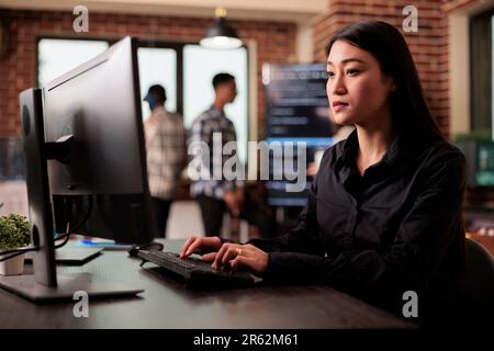 Asian software developer working with html script on terminal window, sitting at desk analyzing javascript code. Freelance coder writing innovating ai algorithm working in it programming office Stock Photo