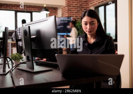 Freelance coder typing machine learning server code, sitting at desk table in it software company. Software developer working on database system with coding script in it developing office Stock Photo