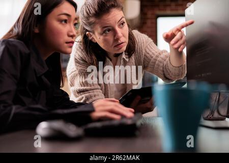 System engineers collaborating on coding project, discussing about programming algorithm for new cloud computing user interface. Diverse team of software developers running database system code. Stock Photo