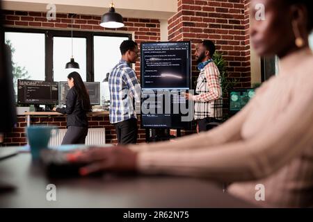 Two of company programming engineers analyzing html code standing in front of big screen, checking errors in artificial intelligence project. Programmers working on machine learning software Stock Photo