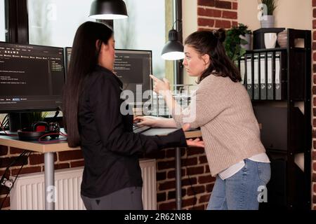 Diverse tech enginners developing javascript code and cloud computing in it programming agency. Software developers discussing database on terminal window, analyzing html script language. Stock Photo