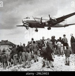 Berliners watching a C-54 land at Berlin Tempelhof Airport during the Berlin Airlift in 1948. In response escalating tensions and to the establishment of.a new West German currency, the Soviets cut off all land communications to West Berlin and stopped sending food there. TheAllied response was an eleven month campaign to supply W Berlin with the 5000 tons per day of food and fuel it needed. A plane landed every three minutes day and night and the operation was so succesful that the Soviets had to back down and reopen the roads, railways and canals. Stock Photo