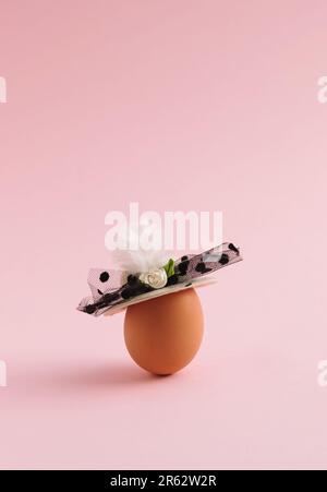 Abstract Easter composition made of boiled egg and woman's hat on pastel pink background. Copy space. Minimalism. Stock Photo